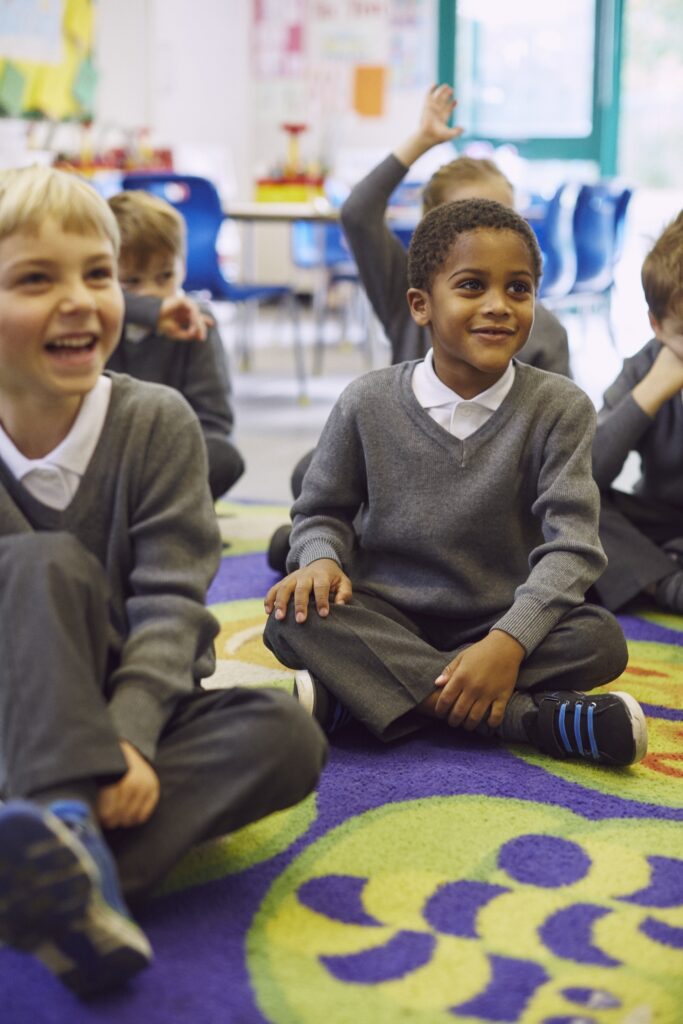 Children enjoying story time on a colorful classroom rug.